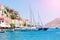 Wonderful view on colorful houses on rocks and sailing boats on dock of deep blue Mediterranian sea on Greek island Symi on sunbea