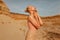 Wonderful woman in splendid slim gold dress posing in desert at the sunset. Profile portrait of a sensual model