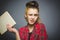 Wondering and stressed girl with book. Closeup teen on grey background