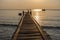 A wonky wooden jetty pier goes out in to a calm sea with small b