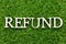 Wood alphabet in word refund on artificial green grass background