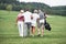 Wood in background. Friends walking through the sport field with golf sticks and having some fun at weekend