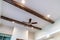 Wood beams and recessed bulbs with ceiling fan and lights at the center