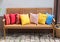 Wood bench outside with much multicolor pillows