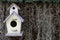Wood bird house on dry grass and green leaf background