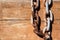 Wood board with iron chain link. Rusted chain hangin in front of a wooden background. Steel chain. Industrial detailed background