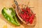 Wood bowl filled with ripe, red chili peppers with artisan spoon and halved friareli pepper  on wood cutting board