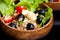 Wood bowl with spelt salad with olives and tomatoes