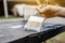 Wood carpenter applies a protective layer of transparent varnish. Hand with a brush close up on the table top