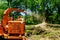 Wood Chipper in Action captures a wood chipper or mulcher shooting chips over a fence.