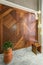 Wood cladding wall, modern glass tall chandelier, tall planter with bushes, and white marble floor