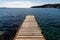 Wood and concrete pier leading out into the clear refreshing waters of the Mediterranean Sea in a picturesque and peaceful cove