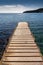 Wood and concrete pier leading out into the clear refreshing waters of the Mediterranean Sea in a picturesque and peaceful cove