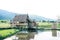 Wood countryside house at the rice fields in thailand with mountain background