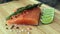 Wood cutting board in kitchen table with fresh red salmon fish salt pepper and lime ready to cook.