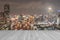 Wood deck in sepia tone with blurred abstract background of night light of Bangkok cityscape on Chao Phraya