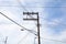 Wood electrical power pole with lines running in multiple directions, street lights and blue sky
