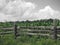 Wood fence in cornfield with cloudy sky