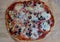 Wood-fired pizza with cheese, tomatoes, olives and finely chopped salami