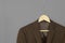 Wood hanger with brown suit isolated on grey background