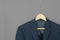 Wood hanger with navy blue suit isolated on grey background