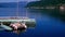 Wood hull catamaran sailboat tied to a pale green dock rocks gently on the calm waters of a fjord in Norway