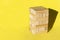 Wood jenga game with wooden block Stack tower on yellow background, manage risk and strategy