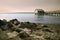 Wood lake pier with a house and a rocky beach