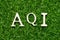 Wood letter in word AQI Abbreviation of air quality index on green grass background