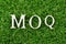 Wood letter in word MOQ Abbreviation of Minimum Order Quantity on green grass background