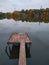 Wood masonry at lake. Rotten pier on the shore of a calm morning reservoir