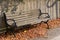 Wood and metal park bench along a sunny sidewalk and modern stone retaining wall