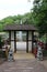 A wood pagoda leading to a viewing platform and seating area over a lake with a water fountain