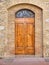 A wood paneled medieval door set into brick arches