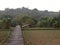 A wood path bridge above rice field. Hill behind rice field. Phonephotography