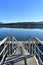 Wood pier and stairs in a bay with water reflections. Forest and beach. Blue sky, sunny day. Galicia, Spain.