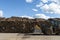 Wood pile wall outside factory with blue sky with a truck