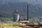 Wood processing plant with tall rusted chimney and storage silo