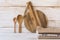 Wood round cutting board, spoons, stack of linen kitchen towels on white plank wood background