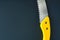 Wood saw blade of handsaw with yellow handle.