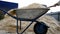 Wood sawdust is poured into a garden cart with a scoop. Fresh, dry pine shavings piled in a heap. Wood waste after wood production
