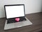 Wood table with blank screen on laptop and pink heat shape sign