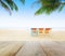 Wood table top on blur beach background with beach chairs under coconut tree