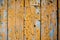 Wood texture with yellow flaked paint. Peeling paint on weathered wood