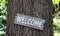 Wood welcome sign hanging on tree in forest