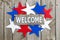 Wood welcome sign surrounded by red, white and blue stars