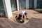 Wood worker sand and cleans wooden deck with power sander tool