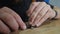 A woodcarver cuts an Orthodox ebony cross with a knife. an artisan carves a carving on a wooden cross