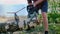 A woodcutter, logger saws a wood with a chainsaw on the beach of a lake, river