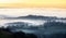 Wooded valley shrouded in mist at sunset in the English countryside with mysterious sky